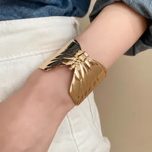 Statement gold butterfly wing cuff bracelet featuring irregular pleated mirror finish design