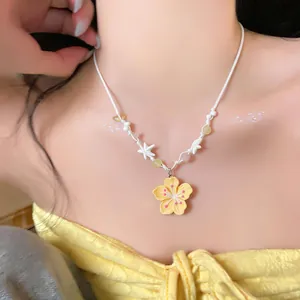 Close-up of cute yellow flower pendant necklace with white star beads and woven cord.