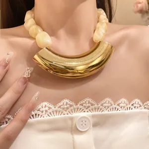 Close-up detail of retro acrylic bead necklace featuring a bold gold curved metal pendant