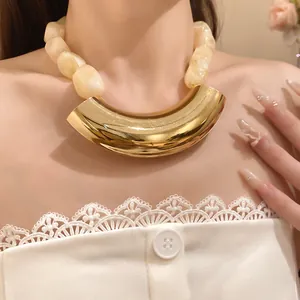 Close-up detail of acrylic beaded necklace featuring a polished curved gold-tone metal pendant