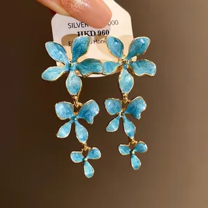 Elegante blaue Emaille-Blumenohrringe mit Silbernadeln und goldfarbenem Finish.
