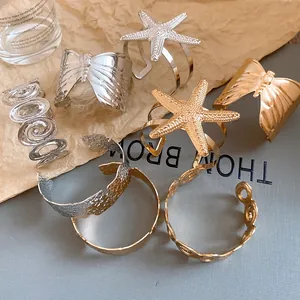 Detailed view of various metallic bracelets featuring starfish, butterfly, and pleated designs