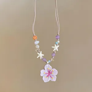 Close-up of pastel purple flower pendant necklace accented with cream starfish and beads