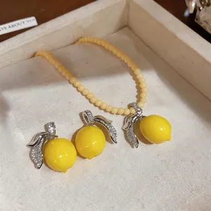 Detailed view of yellow lemon pendant necklace and matching earrings set with zircons