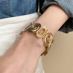 Close-up of gold open cuff bracelet with irregular swirl and oval circular patterns