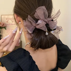 Vue détaillée d'un accessoire cheveux nœud en mousseline mauve avec breloques en cristal