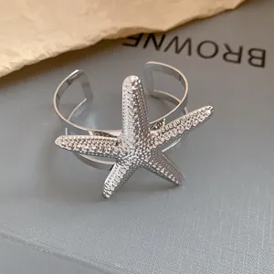 Close-up macro view of a silver starfish cuff bracelet featuring a textured beaded design