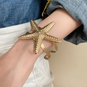Close-up of textured gold starfish open cuff bracelet with irregular double bands.