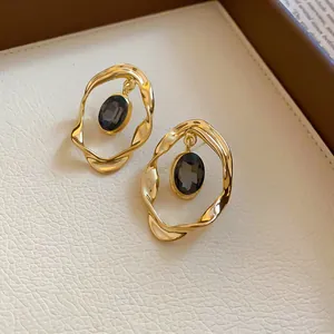 Vintage gold oval crystal stud earrings with irregular pleated metal frame detail