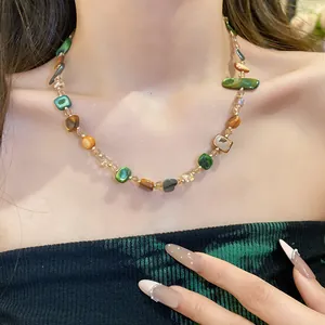 Dettaglio di una collana vintage con perline di conchiglia irregolari indossata da una modella