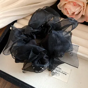 Gros plan sur un chouchou élégant en mousseline noire avec des accents de cristal brillants.
