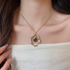 Detail of a vintage gold-toned oval pendant necklace with a grey stone centerpiece.