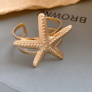 Detailed close-up of a golden starfish open cuff bracelet with intricate textured surface