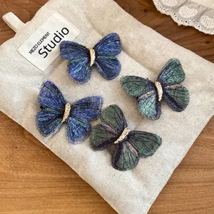 Vintage embroidered butterfly hair clips with gold textured centers on linen background