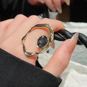 Detail shot of vintage gold irregular wavy ring with black oval gemstone on finger
