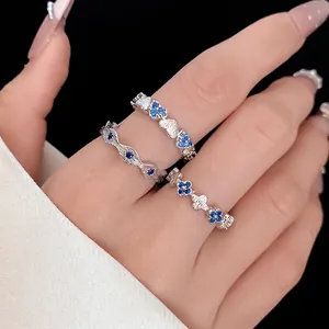 Elegant stackable silver rings set featuring blue heart and clover zircon stones on a hand