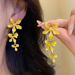 Detaillierte Ansicht eleganter gelber Emaille-Blumen-Quastenohrringe mit Silbernadeln.