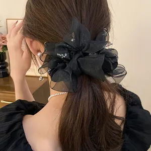 Détail d'un chouchou en mousseline noire avec des accents de cristaux dans les cheveux
