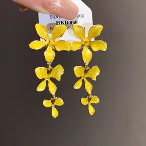 Nahaufnahme von eleganten gelben Emaille-Blumen-Quastenohrringen mit dreischichtigem Design