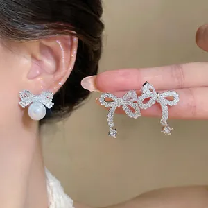 Close-up of elegant silver bow stud earrings with zircons and a white pearl