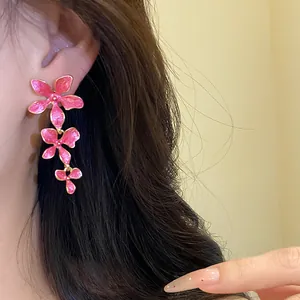 Nahaufnahme von rosa Emaille-Blumen-Quastenohrringen mit Goldrand für einen stilvollen Look