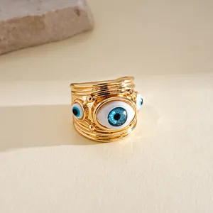 Dettaglio dell'anello aperto dorato con ciondoli occhio di resina blu