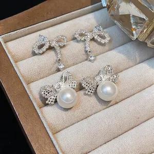 Close-up detail of elegant silver-tone bowtie earrings with sparkling zircons and pearls