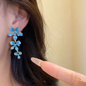 Detailansicht der blauen Emaille-Blumen-Quastenohrringe am Modell im eleganten Stil