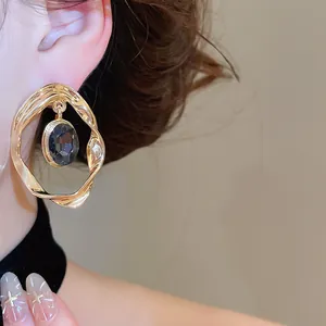 Detail view of vintage style gold twisted hoop earring featuring an oval dark faceted gemstone