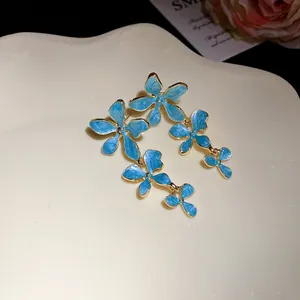 Exquisite Detailansicht blauer Emaille-Blumenohrringe mit edlem goldenem Designrand