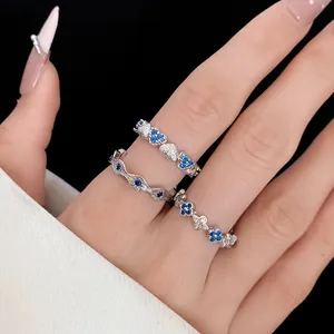 Close-up detail of silver zircon rings with blue heart and floral designs on hand.