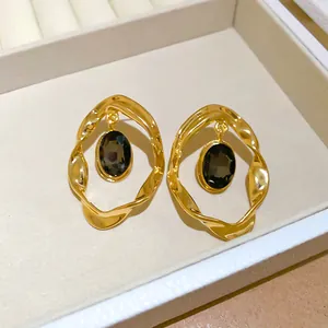 Detail view of vintage style gold-plated oval earrings with dark gemstone inlay.