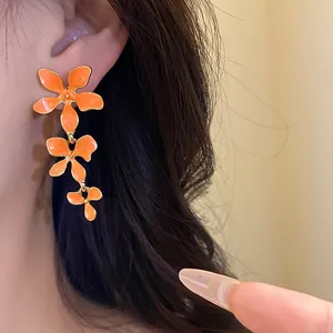 Detailaufnahme von modischen orangefarbenen dreistöckigen Emaille-Blumenohrringen