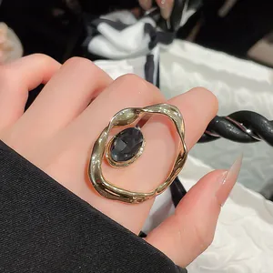 Close-up of a vintage pleated gold ring with an oval black gemstone on a hand.