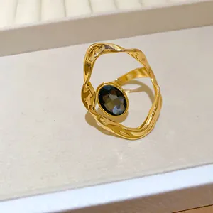 Detail view of vintage gold crumpled ring with an oval dark grey gemstone centerpiece.