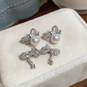 Detailed macro shot of elegant silver bow-knot earrings with shimmering zircon and pearls