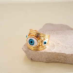 Dettaglio macro di un anello dorato regolabile con vivaci ciondoli occhio malocchio in resina
