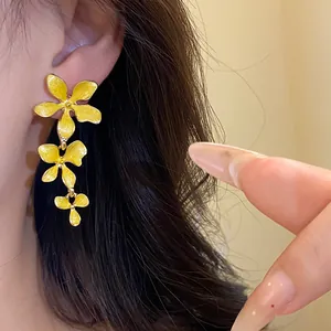 Nahaufnahme gelber Emaille Blumen Quasten Ohrringe am Ohr in elegantem Design getragen