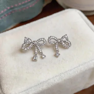 Close-up of elegant bow-knot stud earrings with sparkling zircon stones