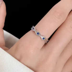 Detail of silver-colored wavy ring with blue zircons and textured band