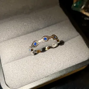 Detailed macro view of a wavy silver ring set with blue zircon stones in a velvet box