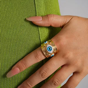 Dettaglio di un anello aperto dorato con occhio in resina sul dito di una modella.
