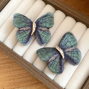 Detailed macro view of two vintage embroidered butterfly hair clips in a jewelry box