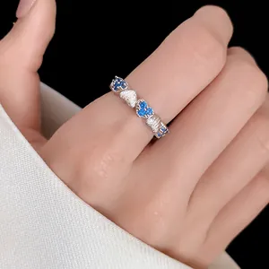 Macro view of a silver heart ring featuring vibrant blue zircon stones on a finger