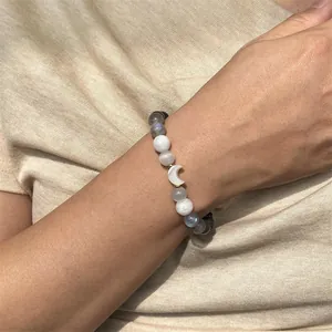 Vue détaillée d'un bracelet en perles de pierre de lune et obsidienne avec charm de lune