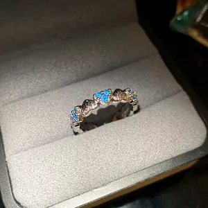 Detailed view of elegant silver heart ring with bright blue zircon stones in a box.