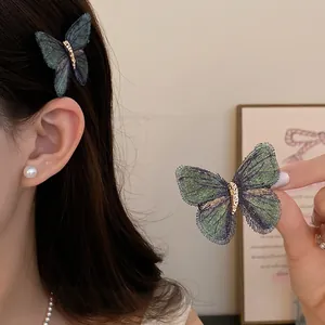 Detail shot of a knitted butterfly hair clip with mesh wings and gold accent.