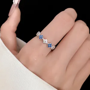 Close-up detail of an elegant zircon clover ring with blue and white stones on a finger