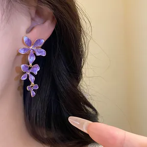 Nahaufnahme von eleganten lila Emaille-Blumen-Quastenohrringen an einem Modellohr