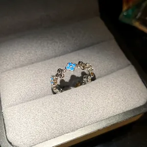 Macro detail of a silver-tone ring with blue clover zircon inlays presented in a jewelry box